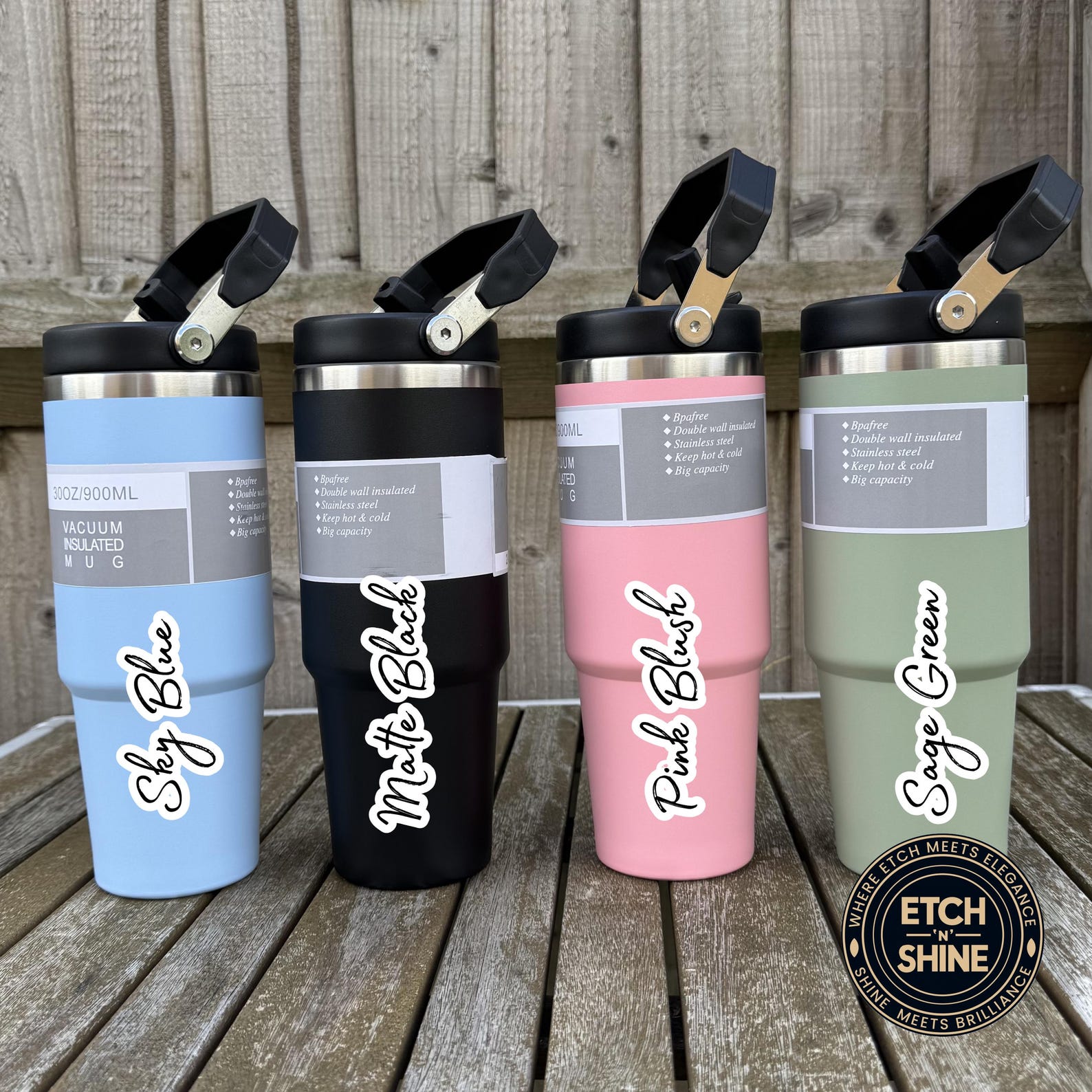 Four tumblers in different colors with names on a wooden surface, branded 'ETCH N SHINE'.