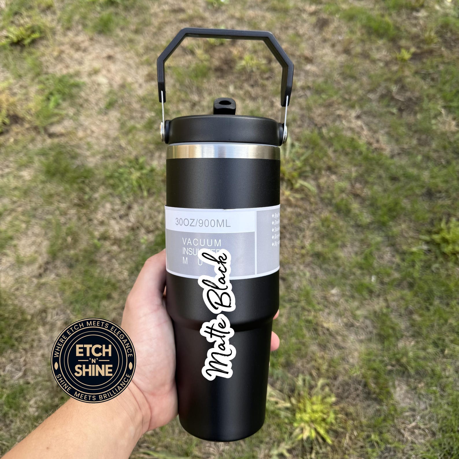 Black insulated water bottle with 'Matte Black' text held by a hand against a grassy background.