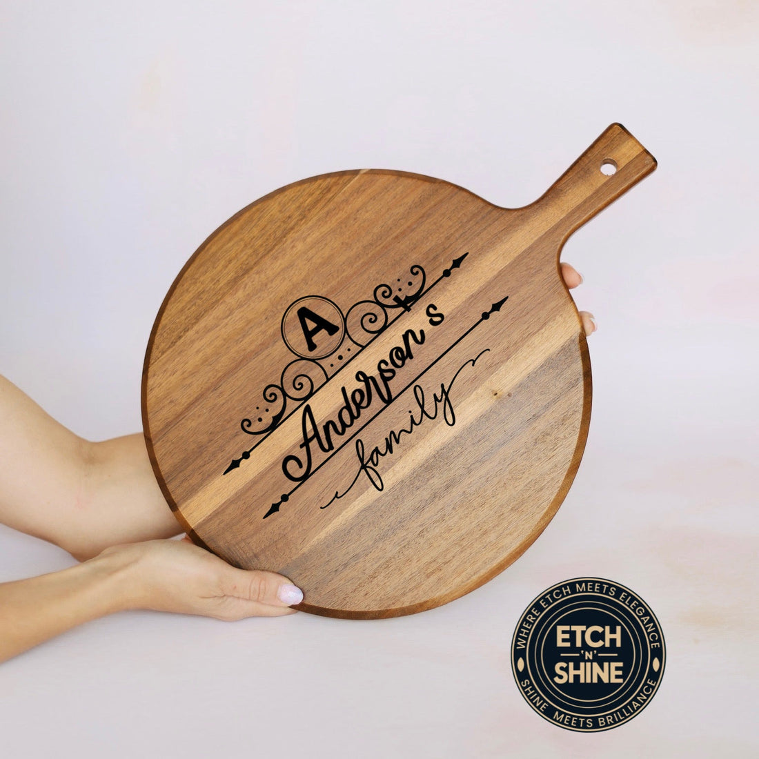 Wooden pizza peel with engraved text held by a person, branded 'Etch of Shine'.