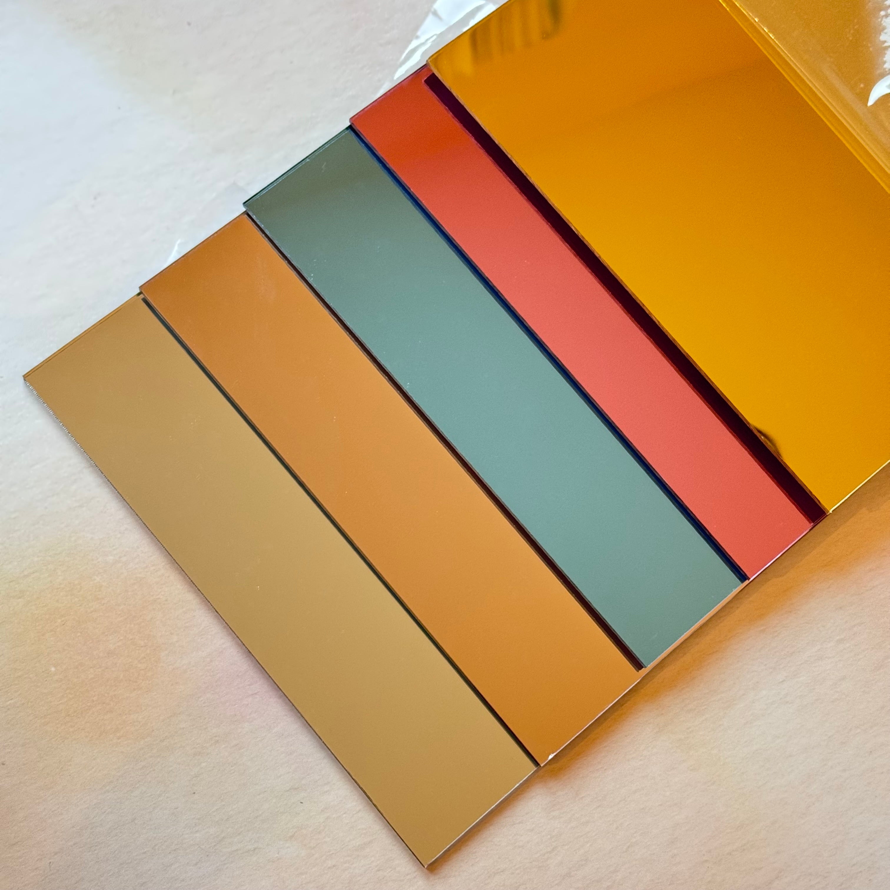 Mirror acrylic sheets fanned out showing warm tone colours – gold, rose gold, pink, blue and silver – Etch 'N' Shine