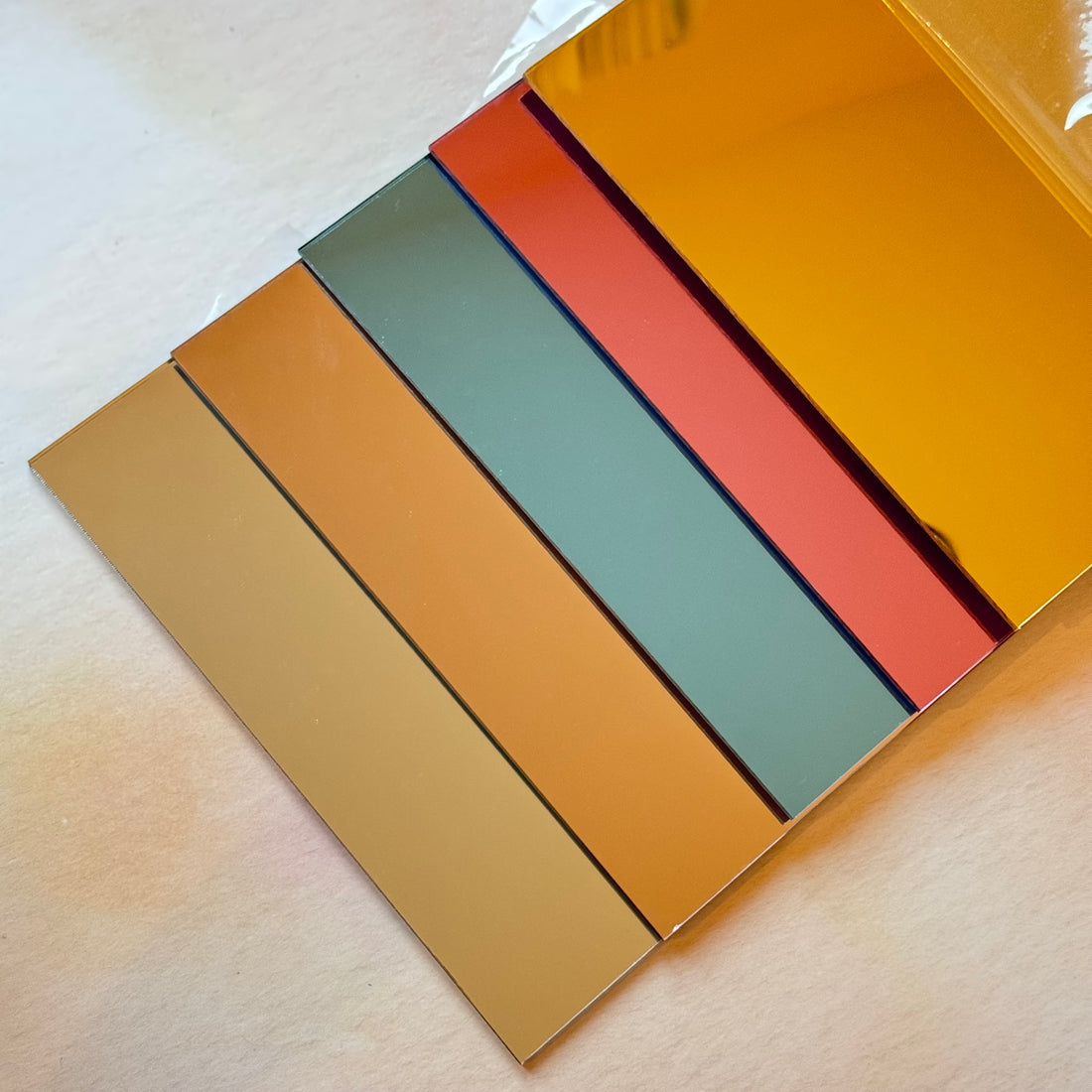 Mirror acrylic sheets fanned out showing warm tone colours – gold, rose gold, pink, blue and silver – Etch 'N' Shine