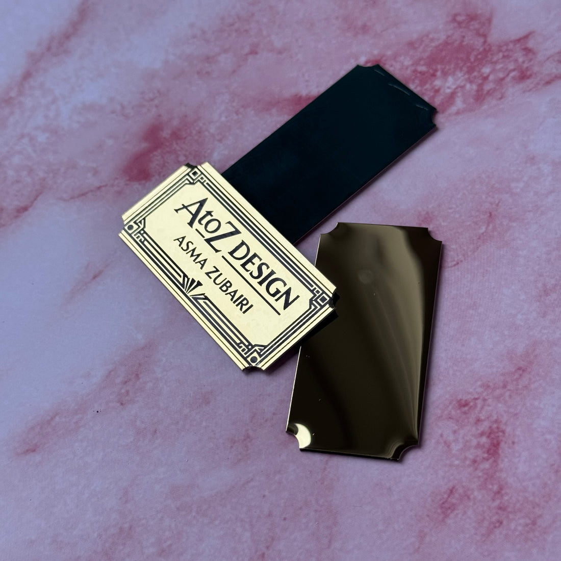Black and gold product with 'AtoZ Design' label on a marbled pink and white background