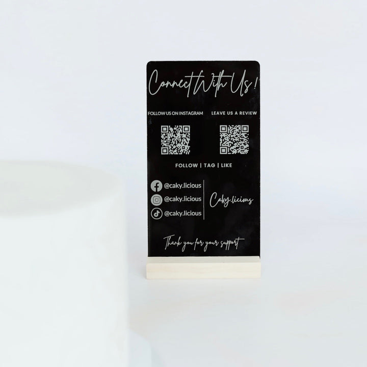 Black business card with white text and QR codes on a white background