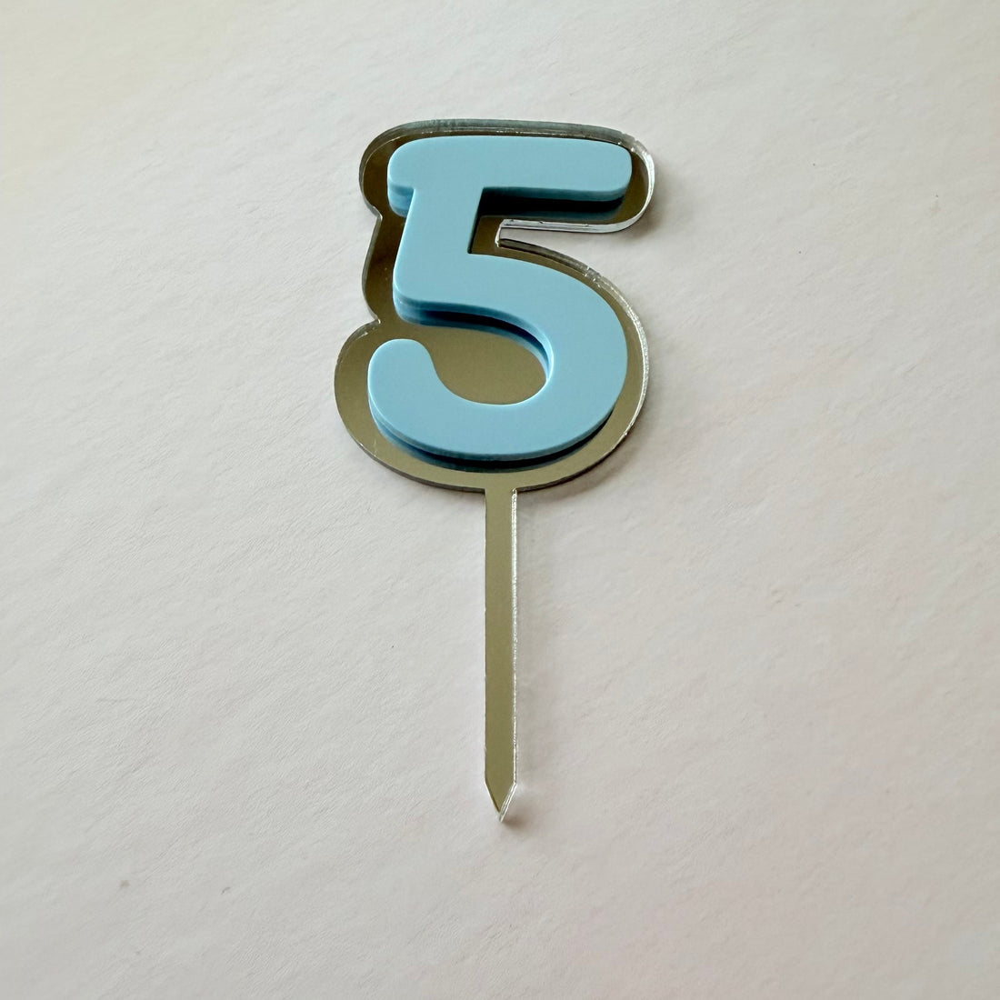 Blue mirror and acrylic double layer number 2 cake topper in a flat lay