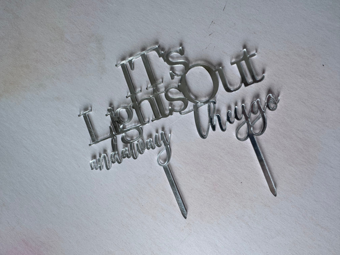 Three silver metal script cake toppers spelling out 'Crazy Love & Mom' arranged on a light off-white background.