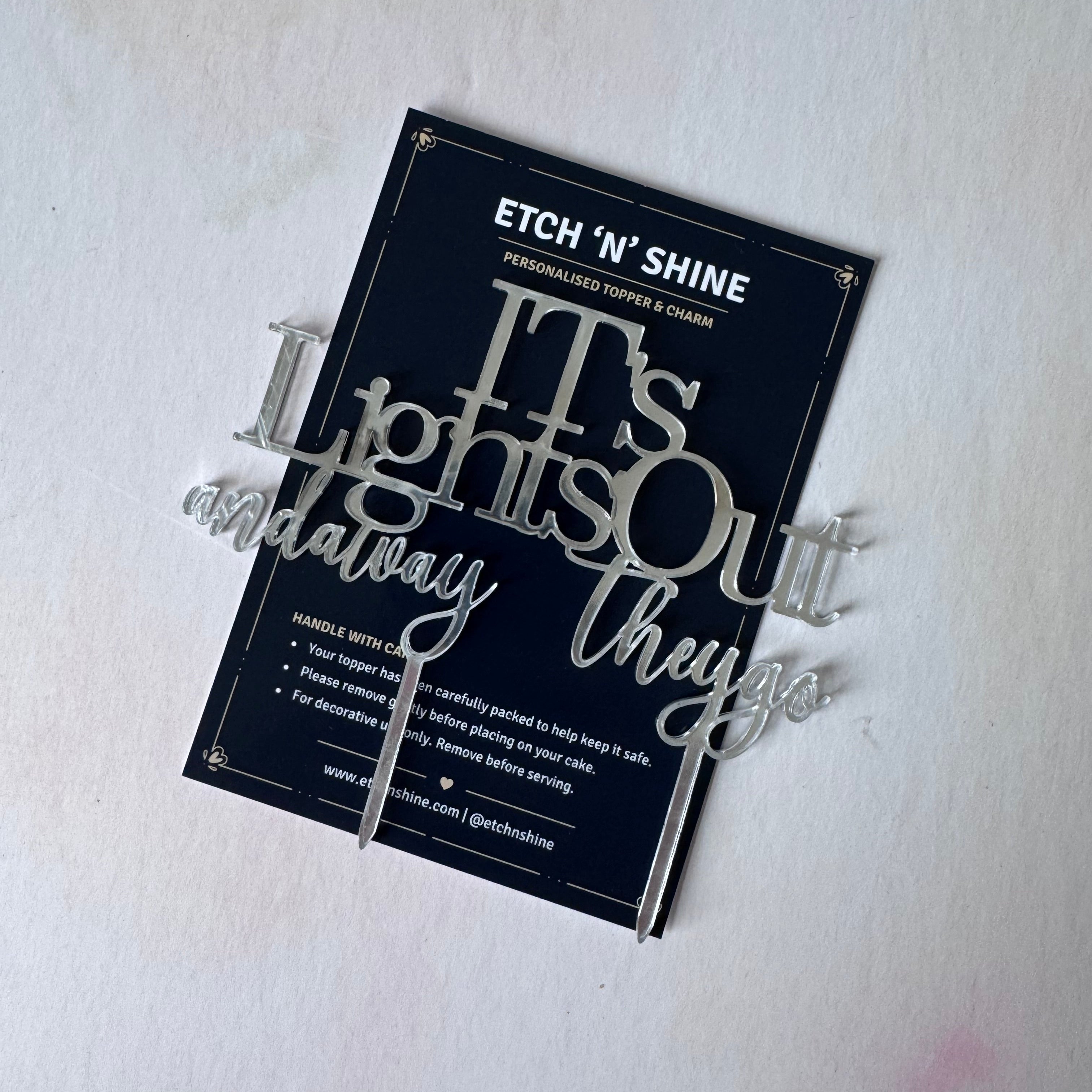 A personalized acrylic sign reading 'It's Lights Out and anyway they go' in silver lettering, displayed on its dark navy backing card against a white background.