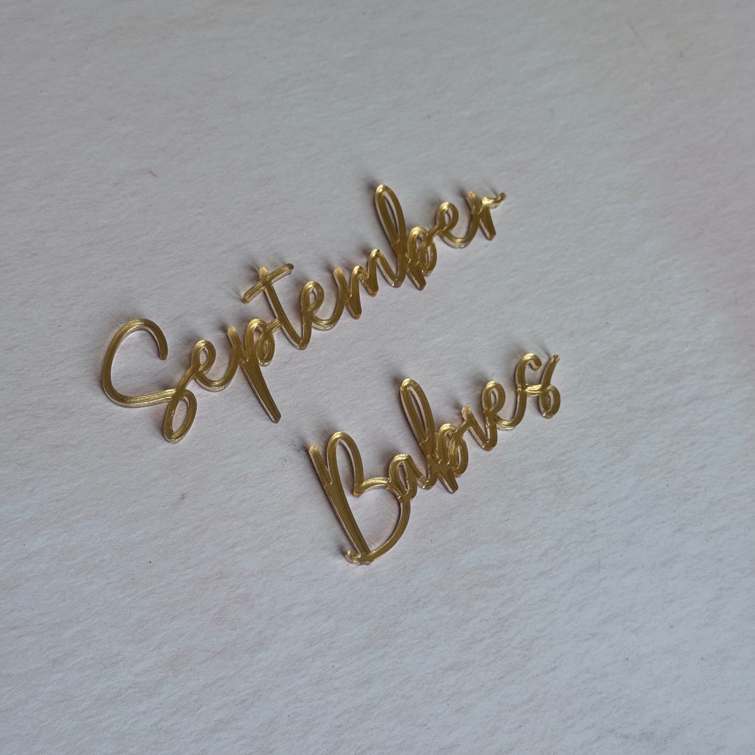 Gold acrylic 'September Babies' script topper flat lay – bespoke laser-cut cake topper – Etch 'N' Shine
