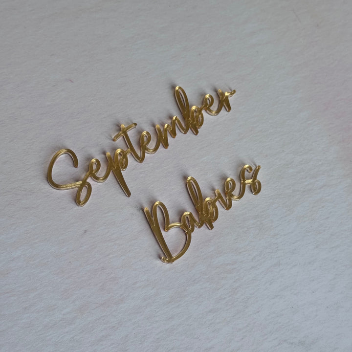 Gold acrylic 'September Babies' script topper flat lay – bespoke laser-cut cake topper – Etch 'N' Shine