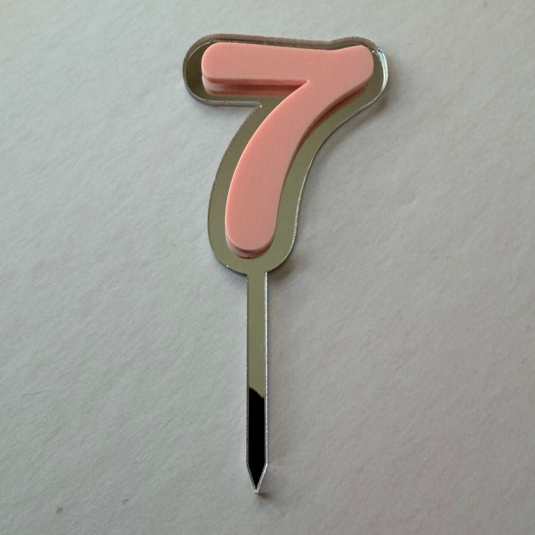 Pink mirror and acrylic double layer number 7 cake topper in a flat lay
