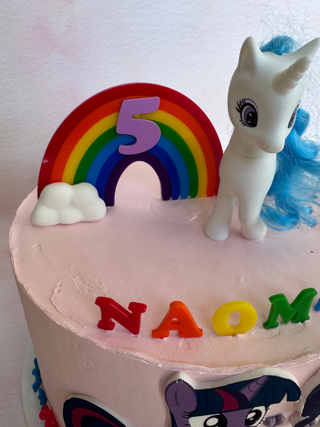 Rainbow acrylic topper and NAOMI letters on a decorated birthday cake, close view – Etch 'N' Shine
