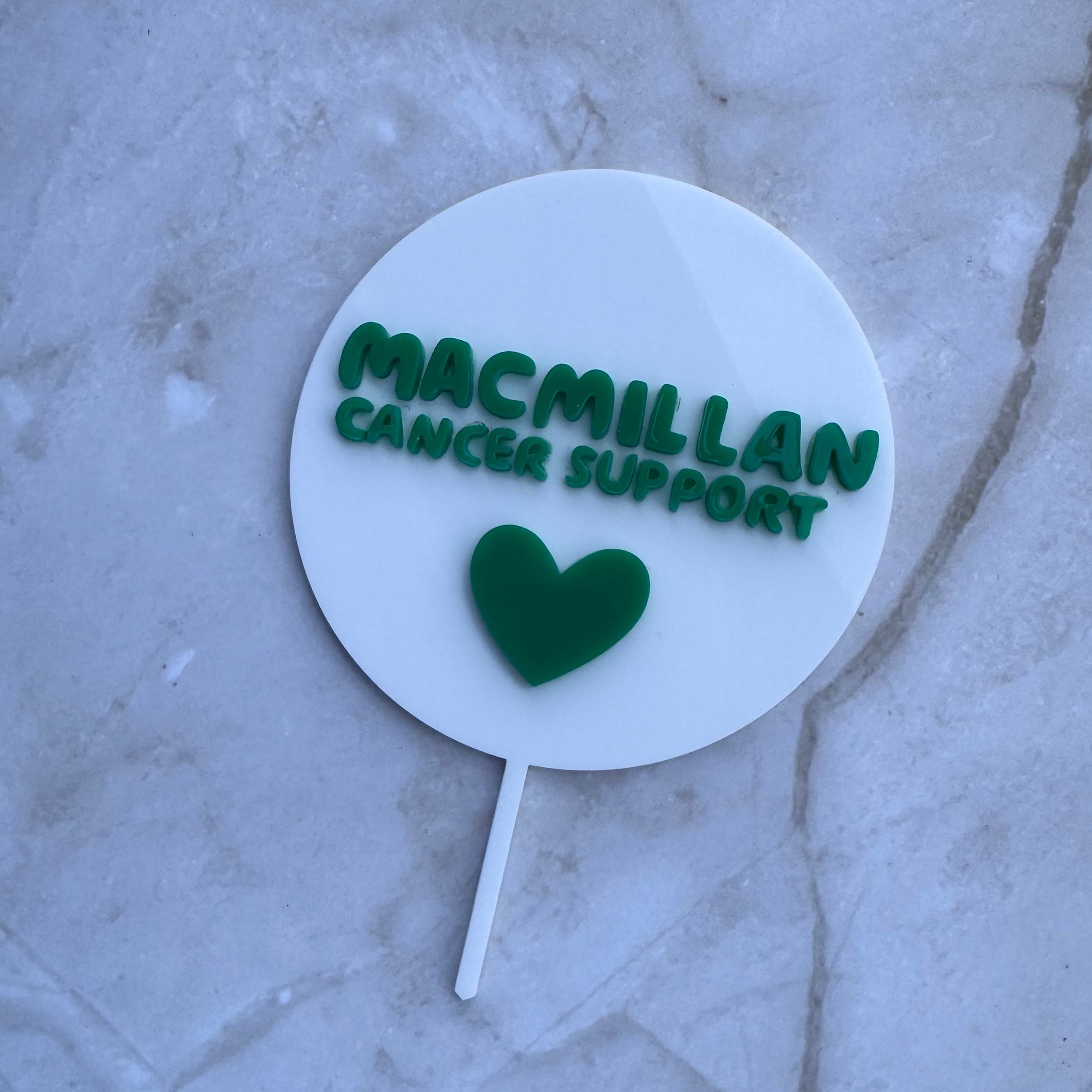 Custom white and green acrylic cake topper shown from an angled view