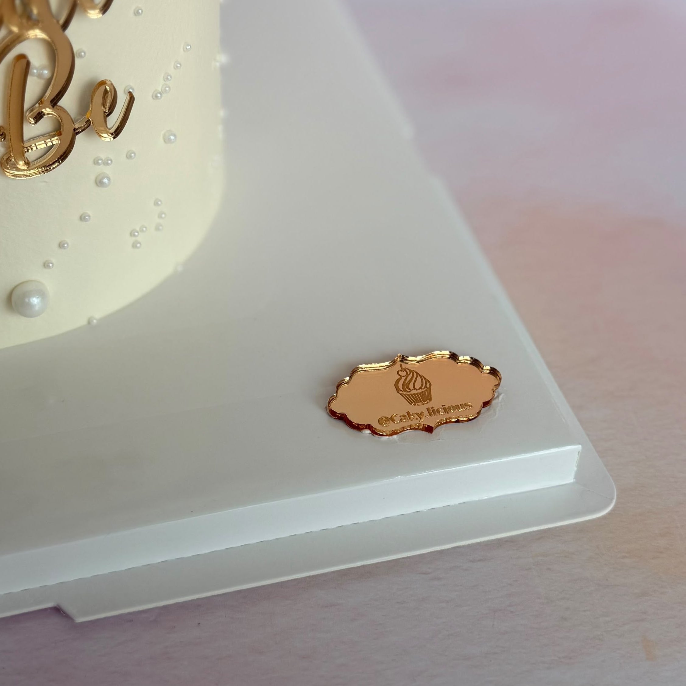 Gold mirror acrylic Bride to Be cake charm displayed on a cake