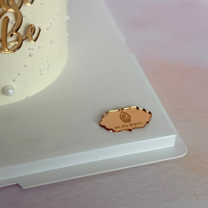 Gold mirror acrylic Bride to Be cake charm displayed on a cake