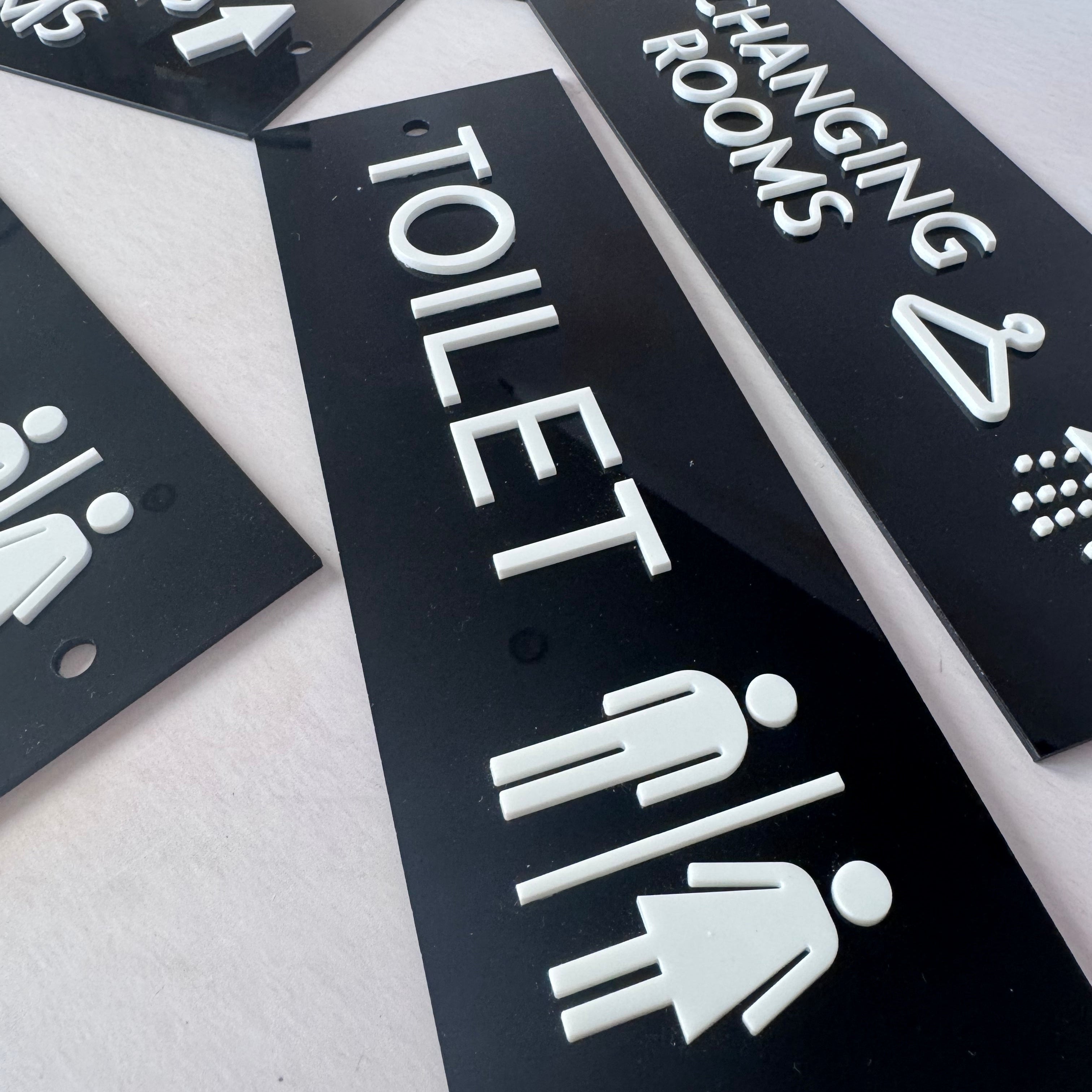 Raised white toilet icon and lettering on black – custom acrylic toilet sign – Etch 'N' Shine