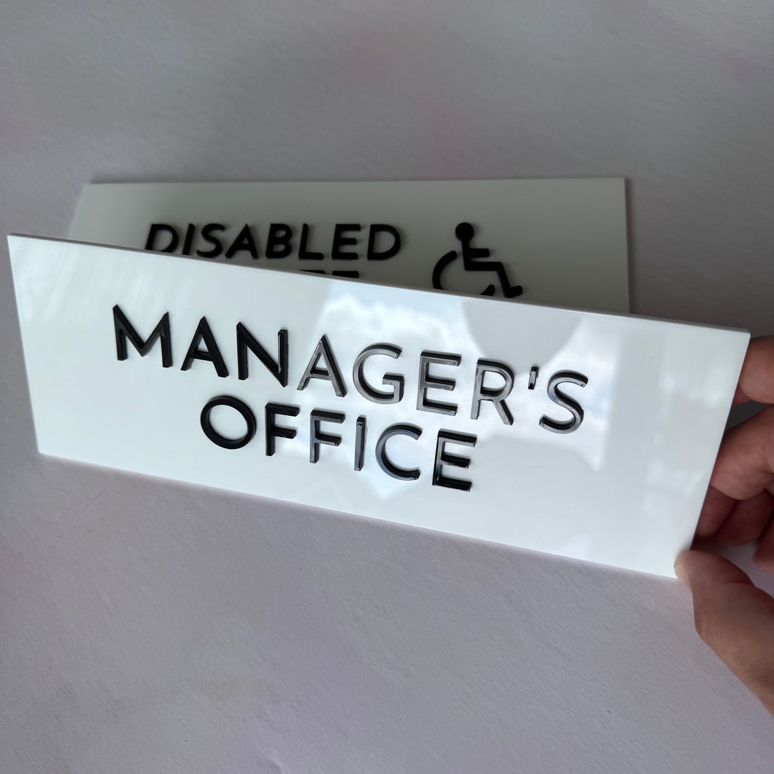 Manager's Office sign held in front of Disabled Toilet sign – white acrylic door signs – Etch 'N' Shine