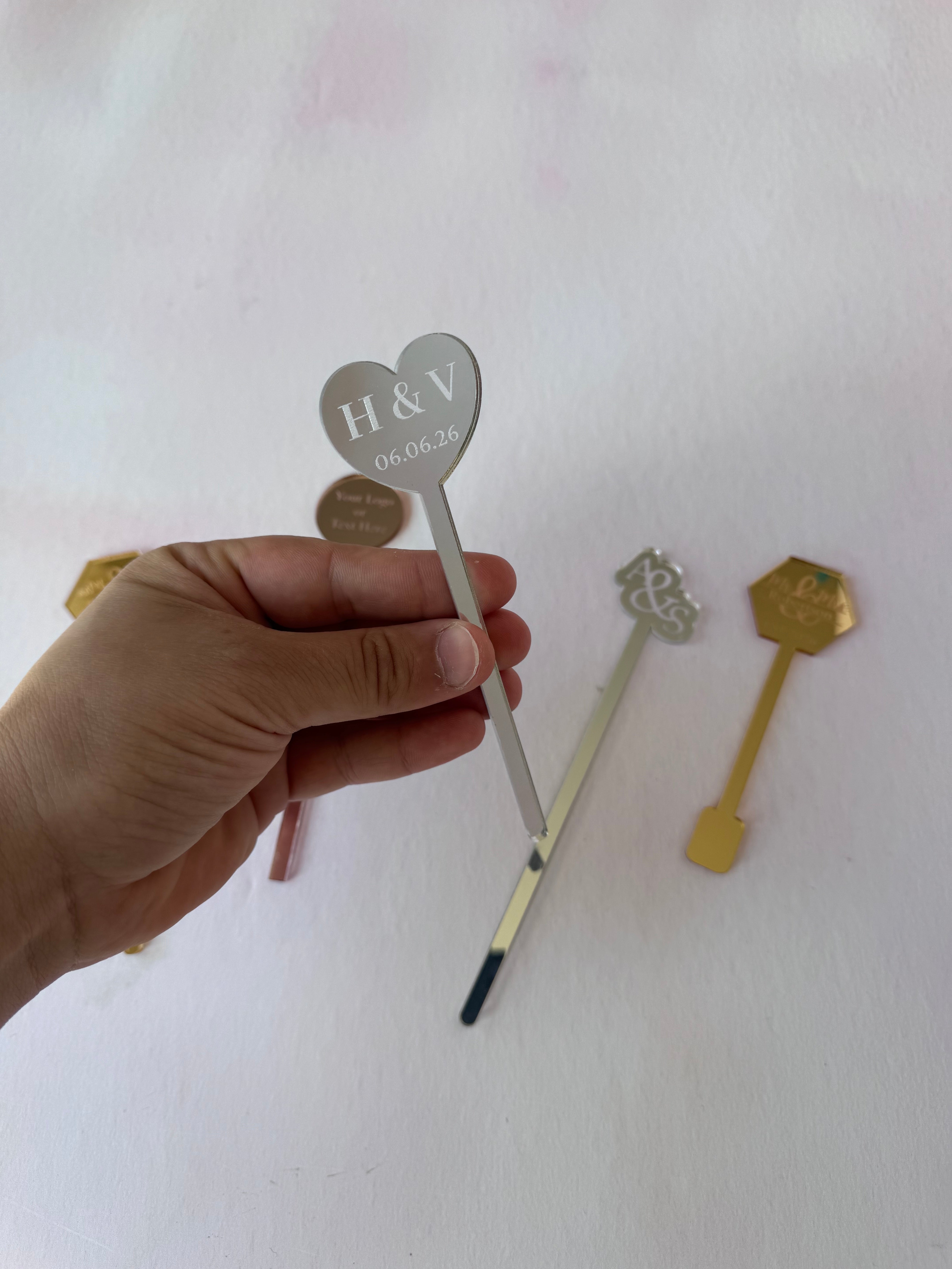 Silver mirror acrylic heart drink stirrer engraved with a date, held in hand – Etch 'N' Shine