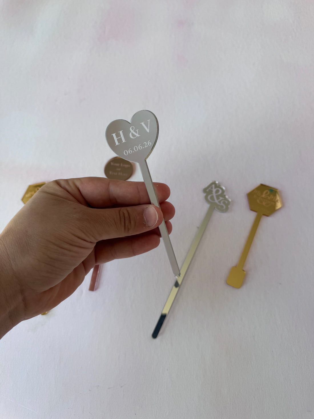 Silver mirror acrylic heart drink stirrer engraved with a date, held in hand – Etch 'N' Shine