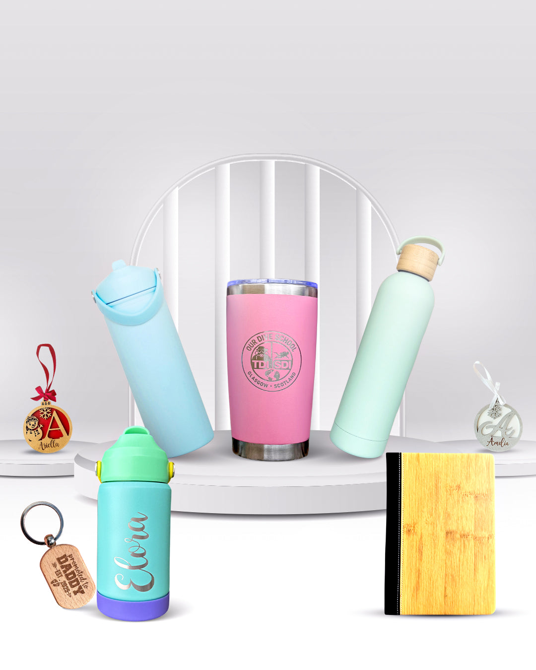 Colorful insulated tumblers and a keychain on a white surface with a clear acrylic stand.