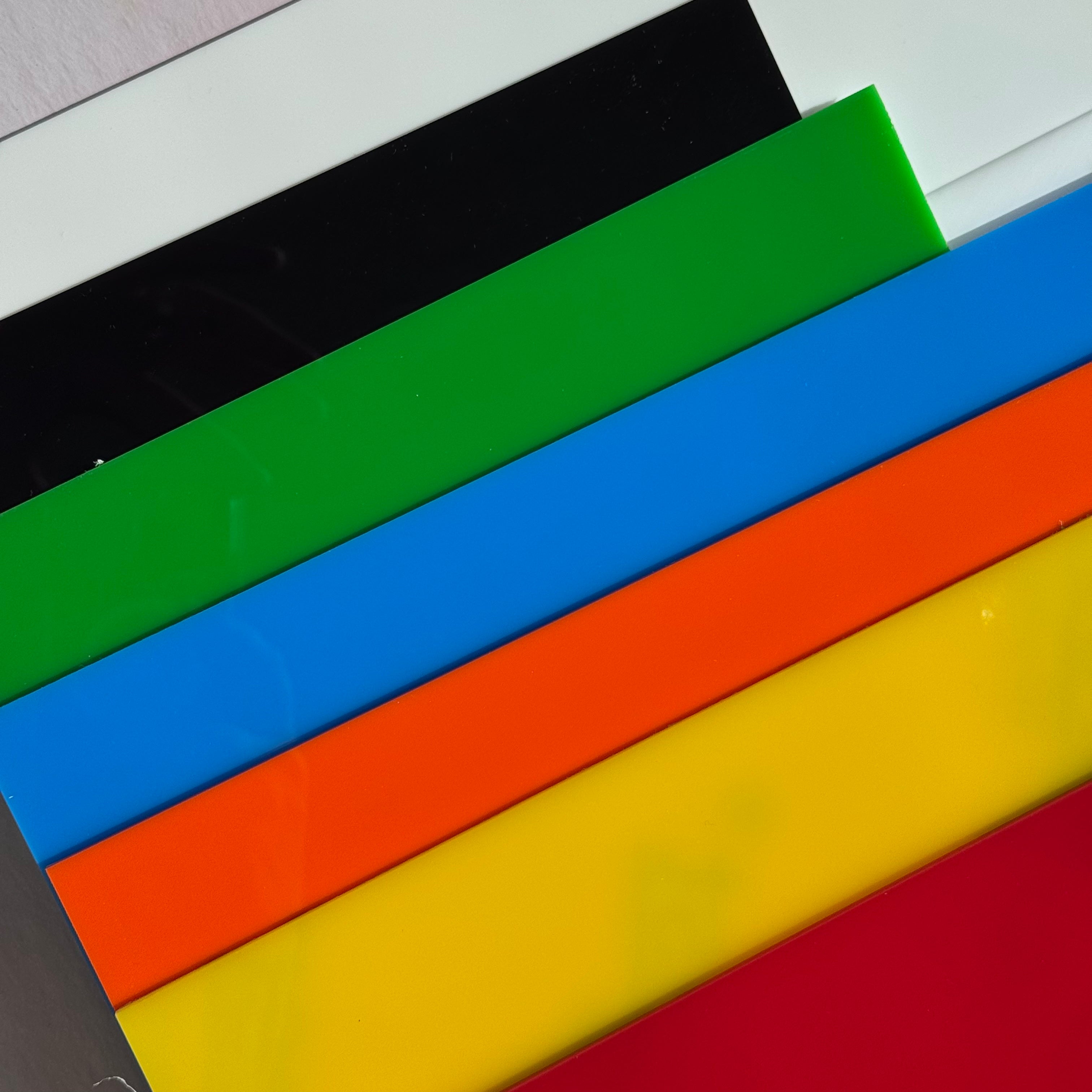Colorful plastic sheets in black, green, blue, orange, yellow, and red on a white background.
