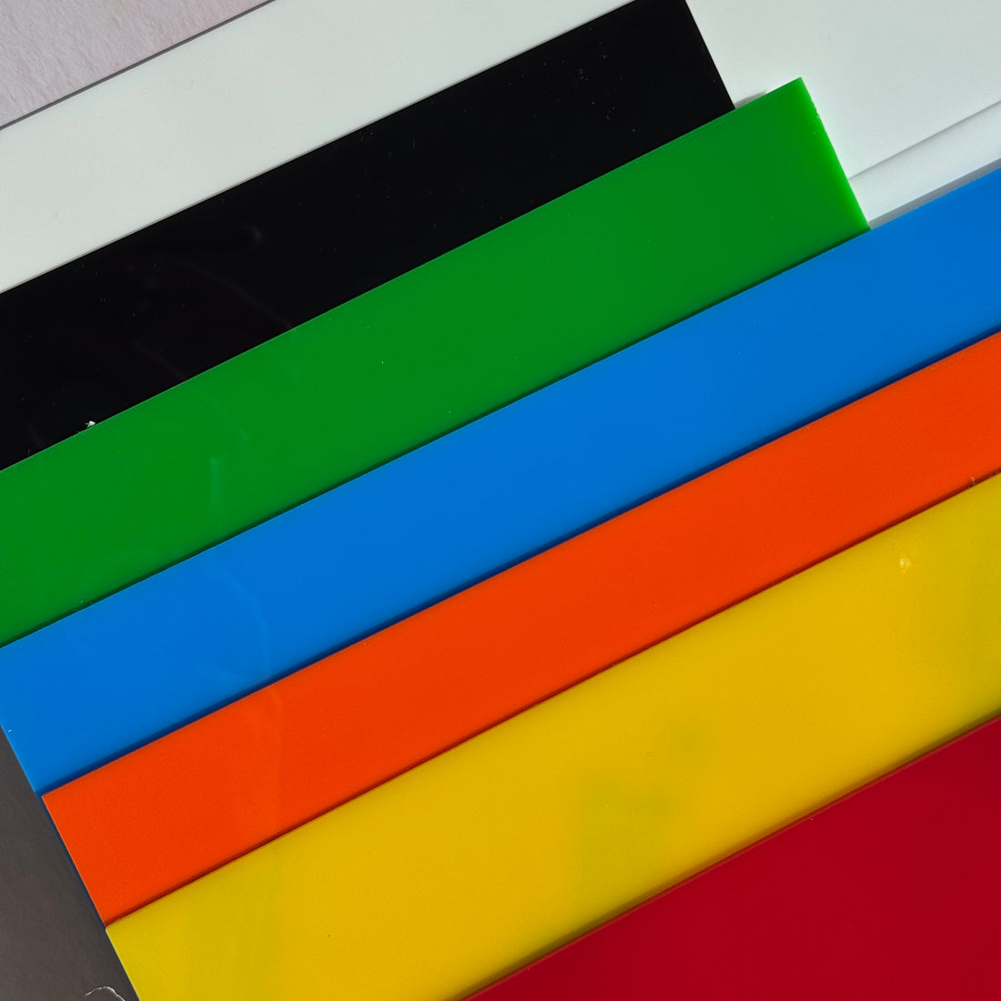 Colorful plastic sheets in black, green, blue, orange, yellow, and red on a white background.