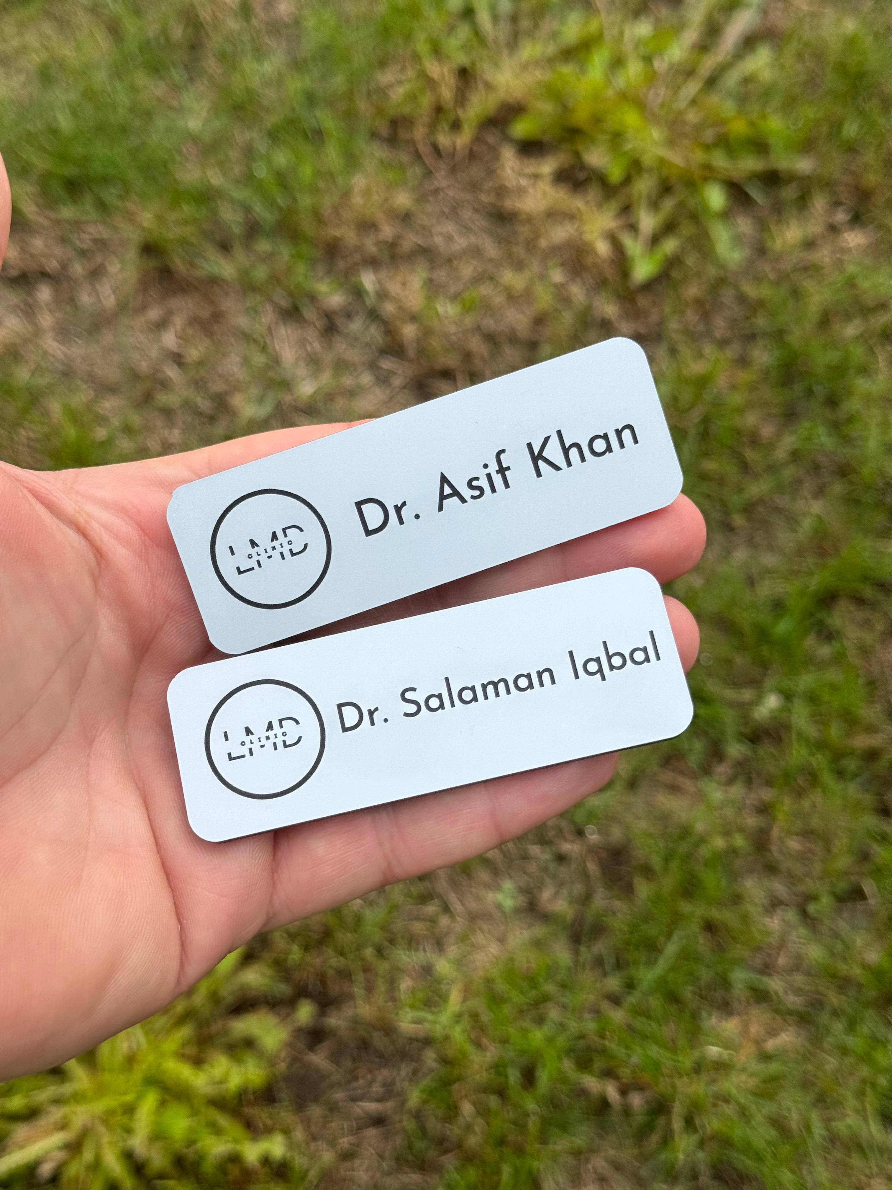 Two name labels held in a hand with a grassy background