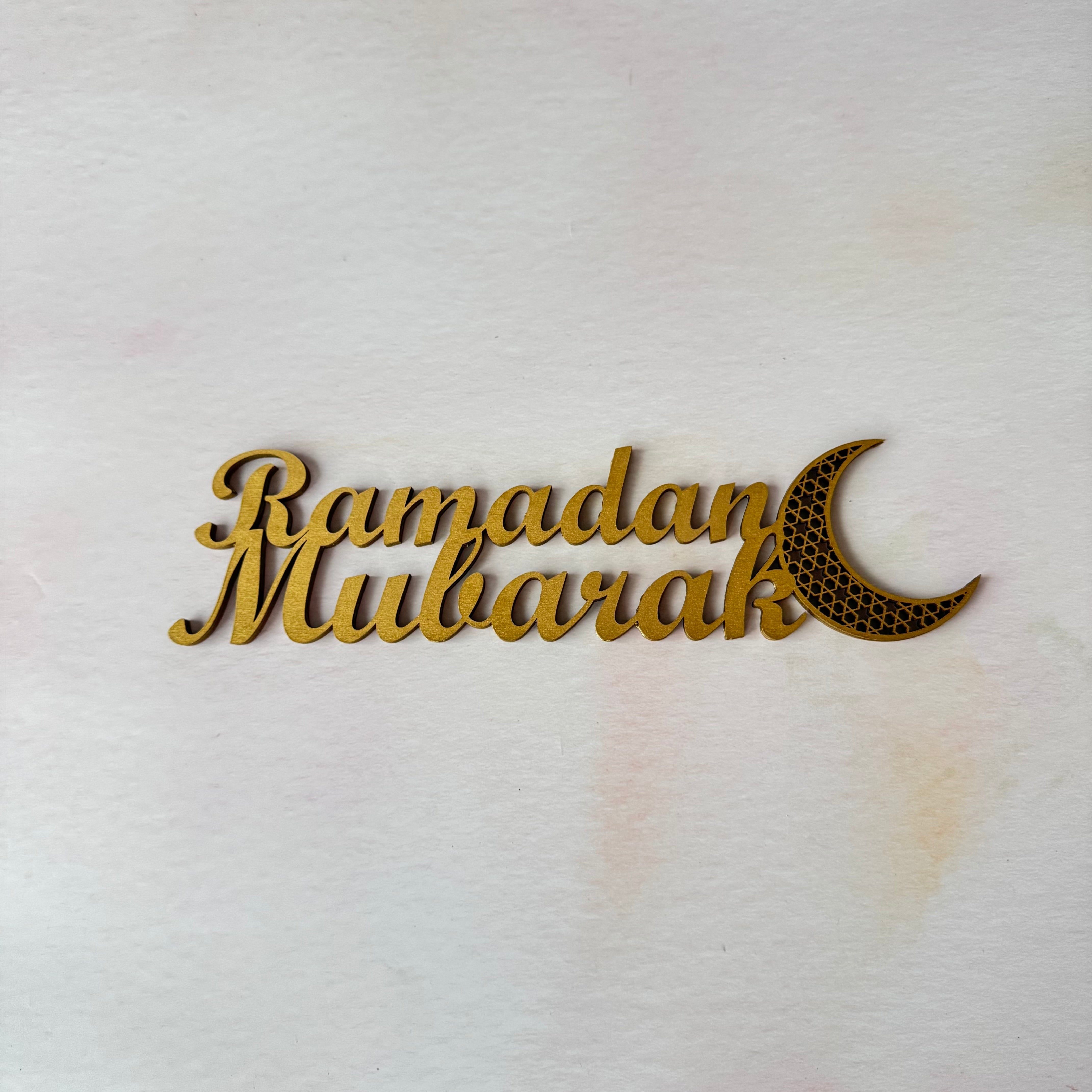 Decorative sign with 'Ramadan Mubarak' text and moon symbol on a white background