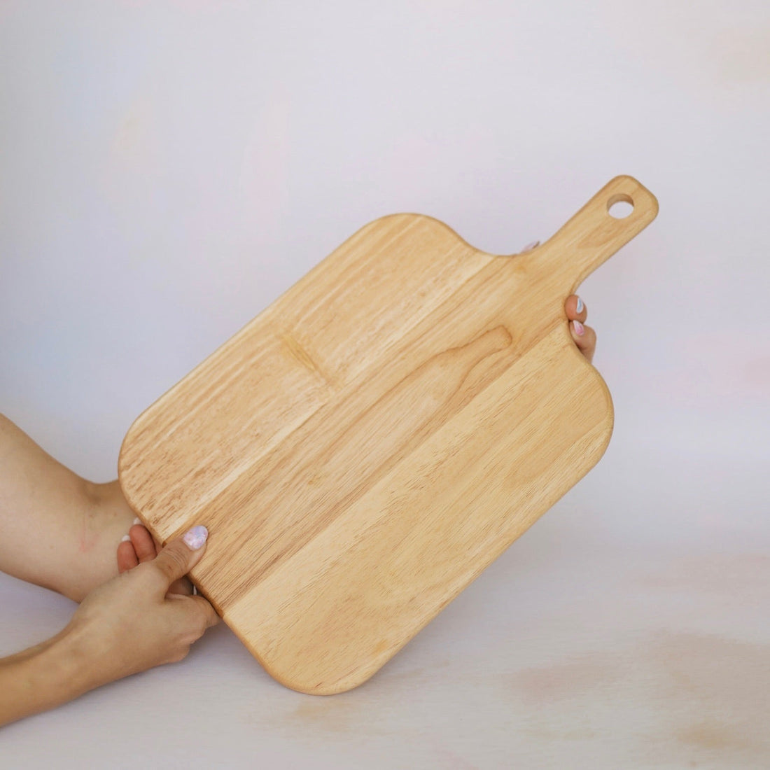 Large oak board held in hand on a bright background