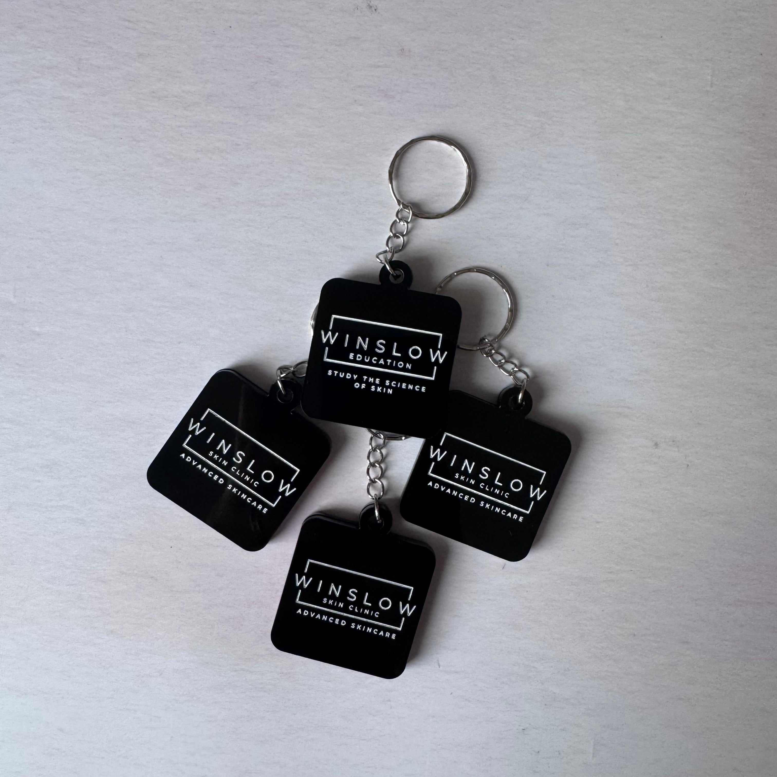 Black square acrylic NFC keyrings with white Winslow Skin Clinic logo and silver rings – Etch 'N' Shine