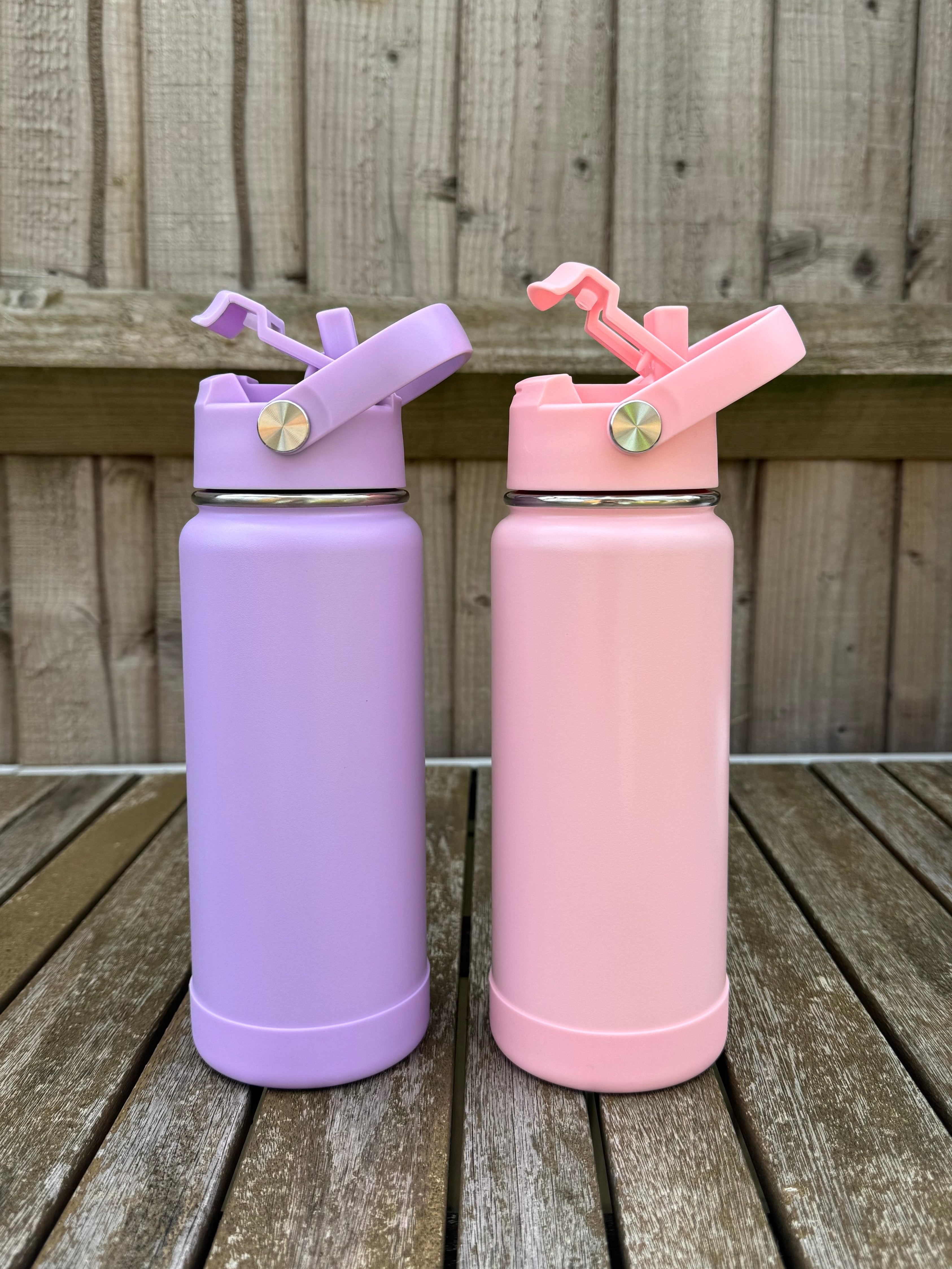 Two pink and purple water bottles with straws on a wooden surface