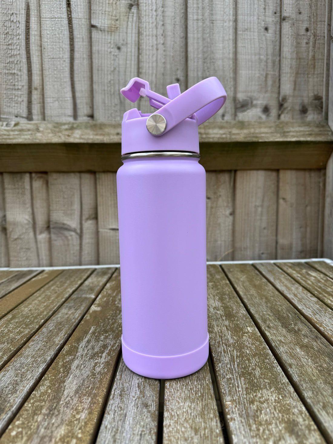 Purple water bottle with a straw on a wooden surface