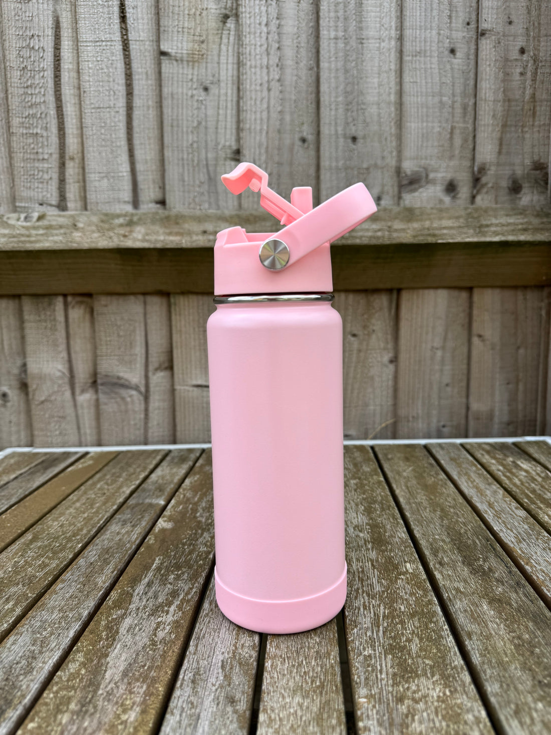 Pink pastel water bottle on a wooden surface