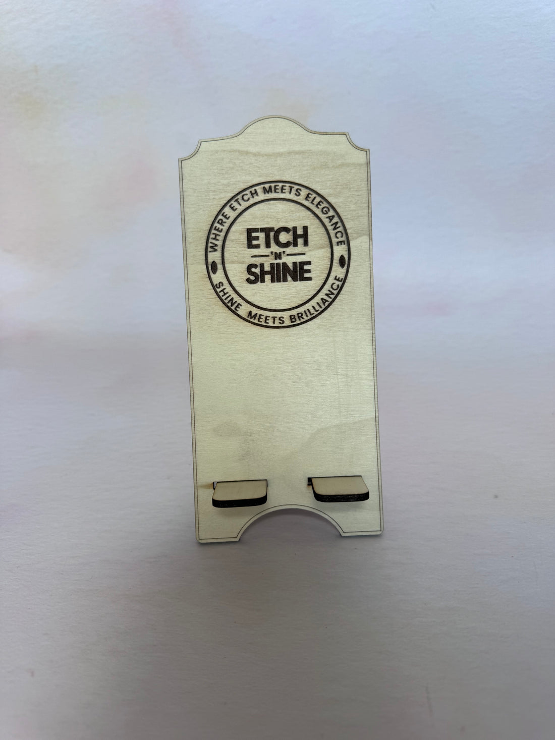 Front of a birch plywood phone stand with an engraved circular logo – Etch 'N' Shine
