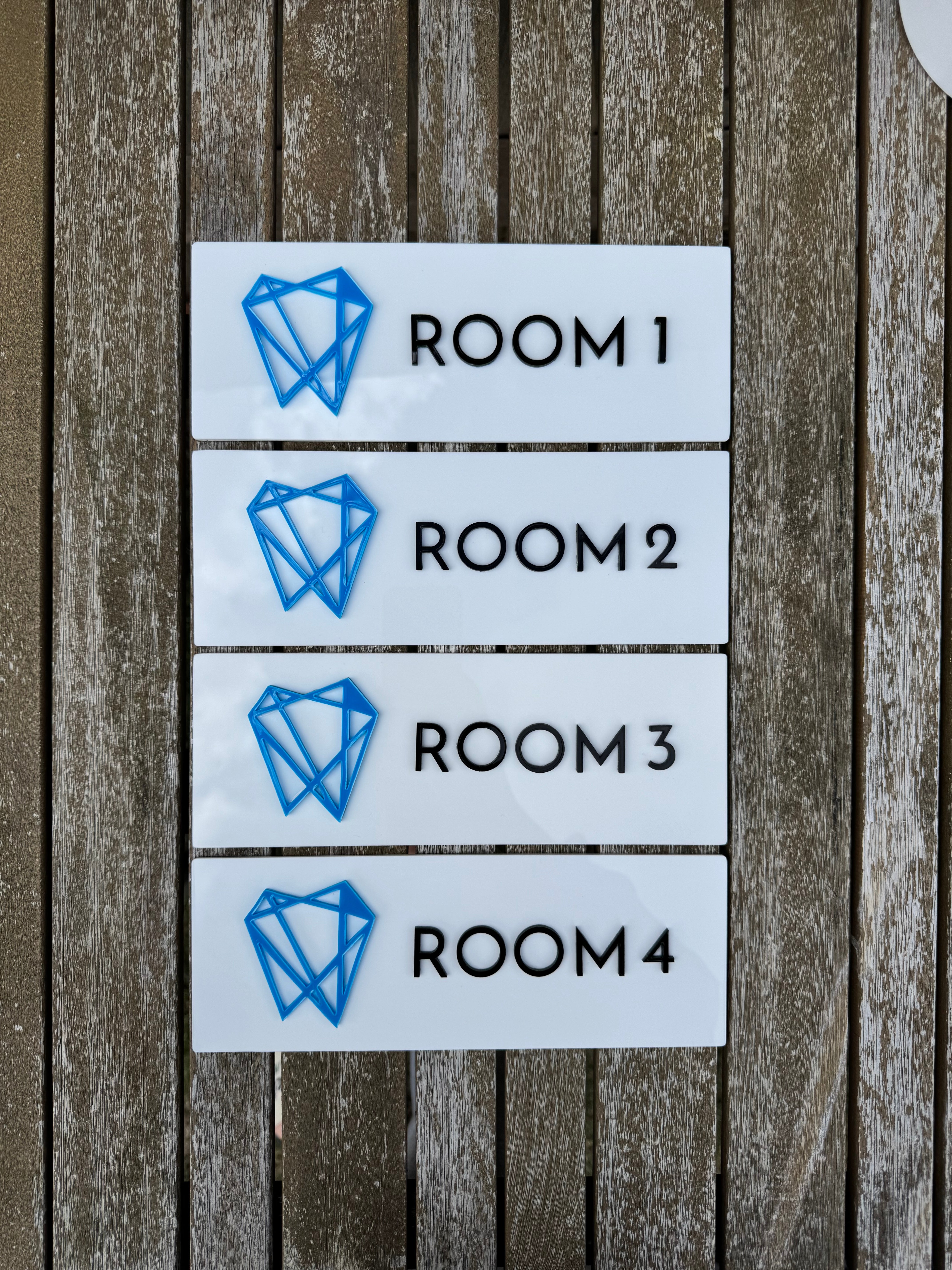 Four room signs labeled 'Room 1' to 'Room 4' on a wooden surface.
