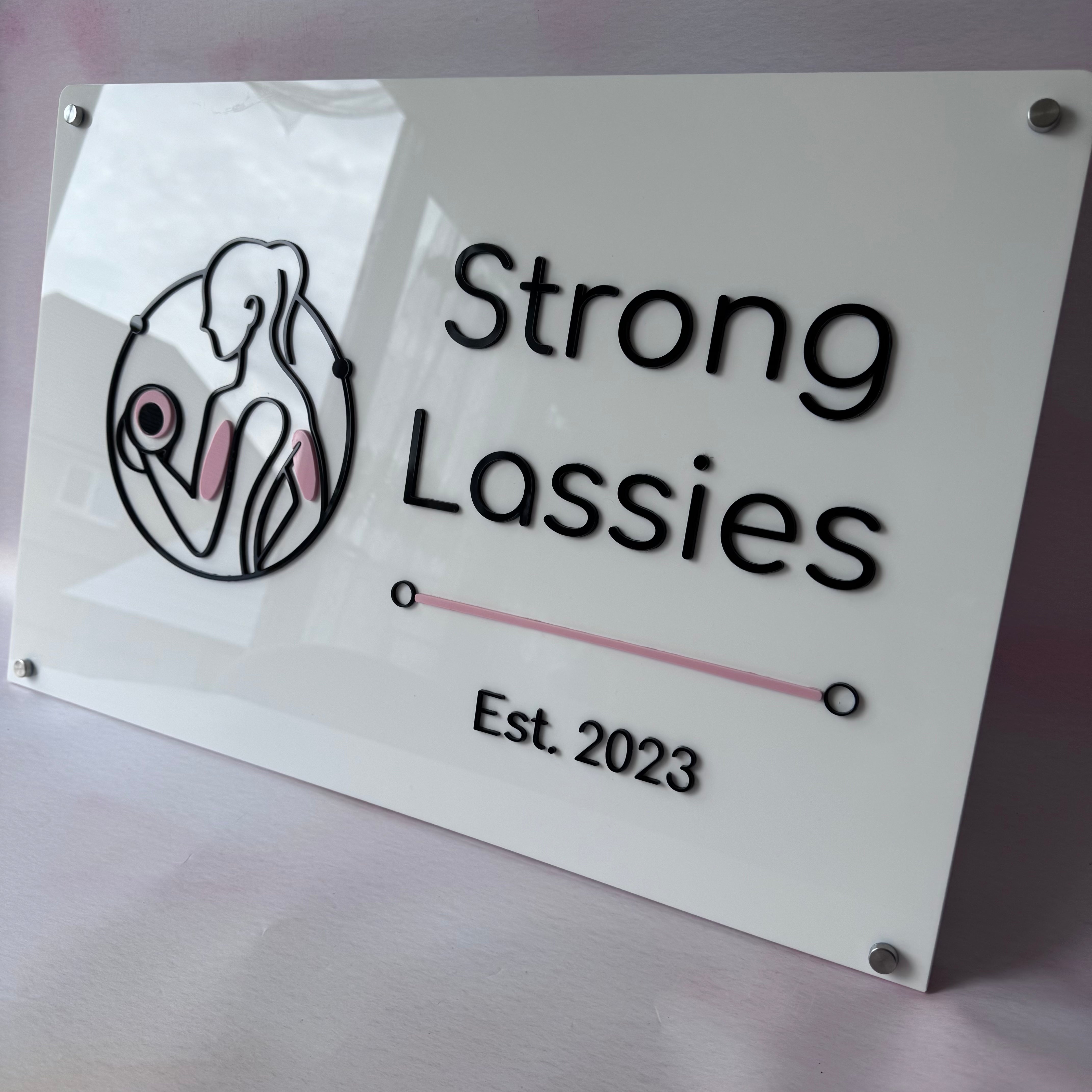 Rectangular white acrylic Strong Lassies logo wall sign with layered lettering
