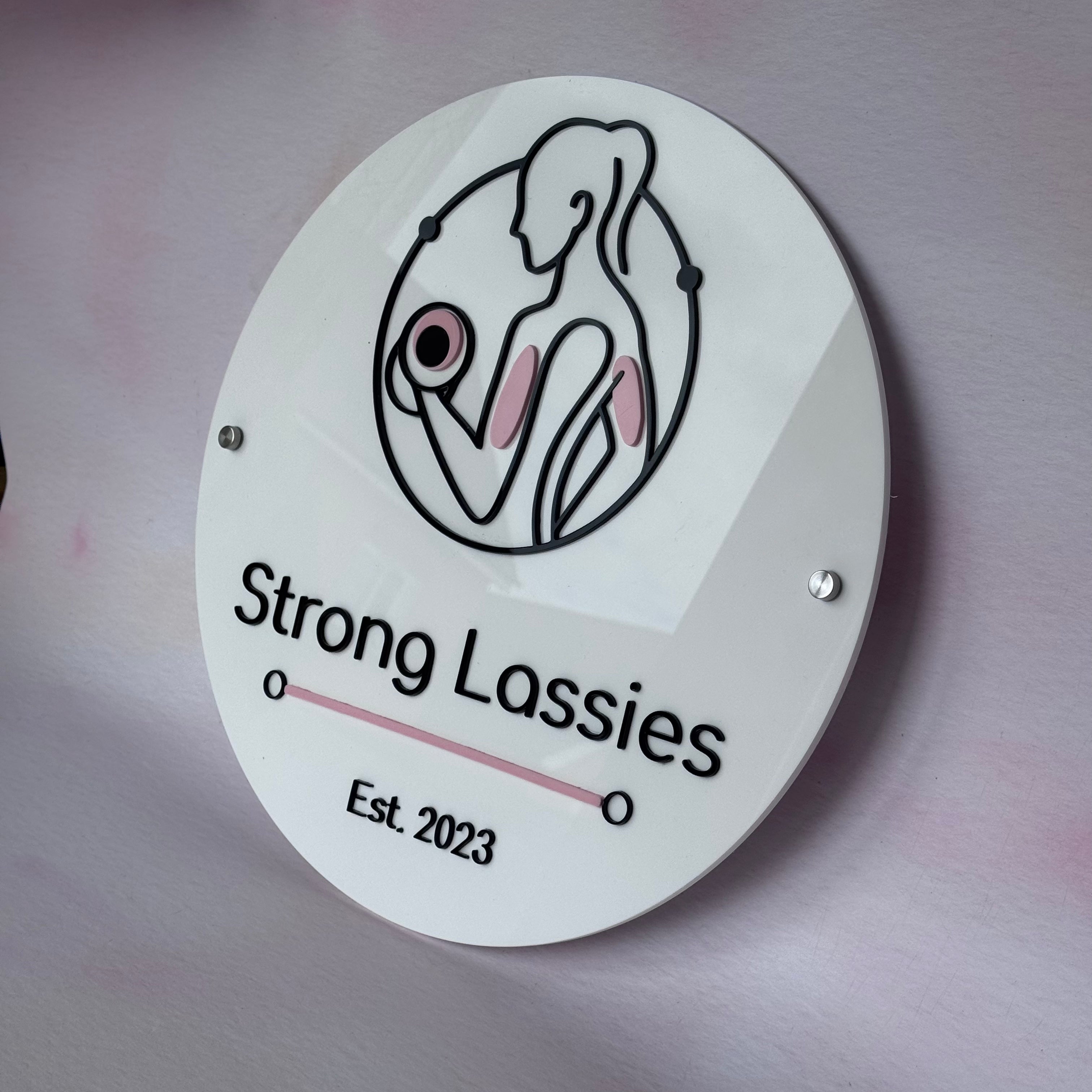 Round white acrylic Strong Lassies business logo wall sign