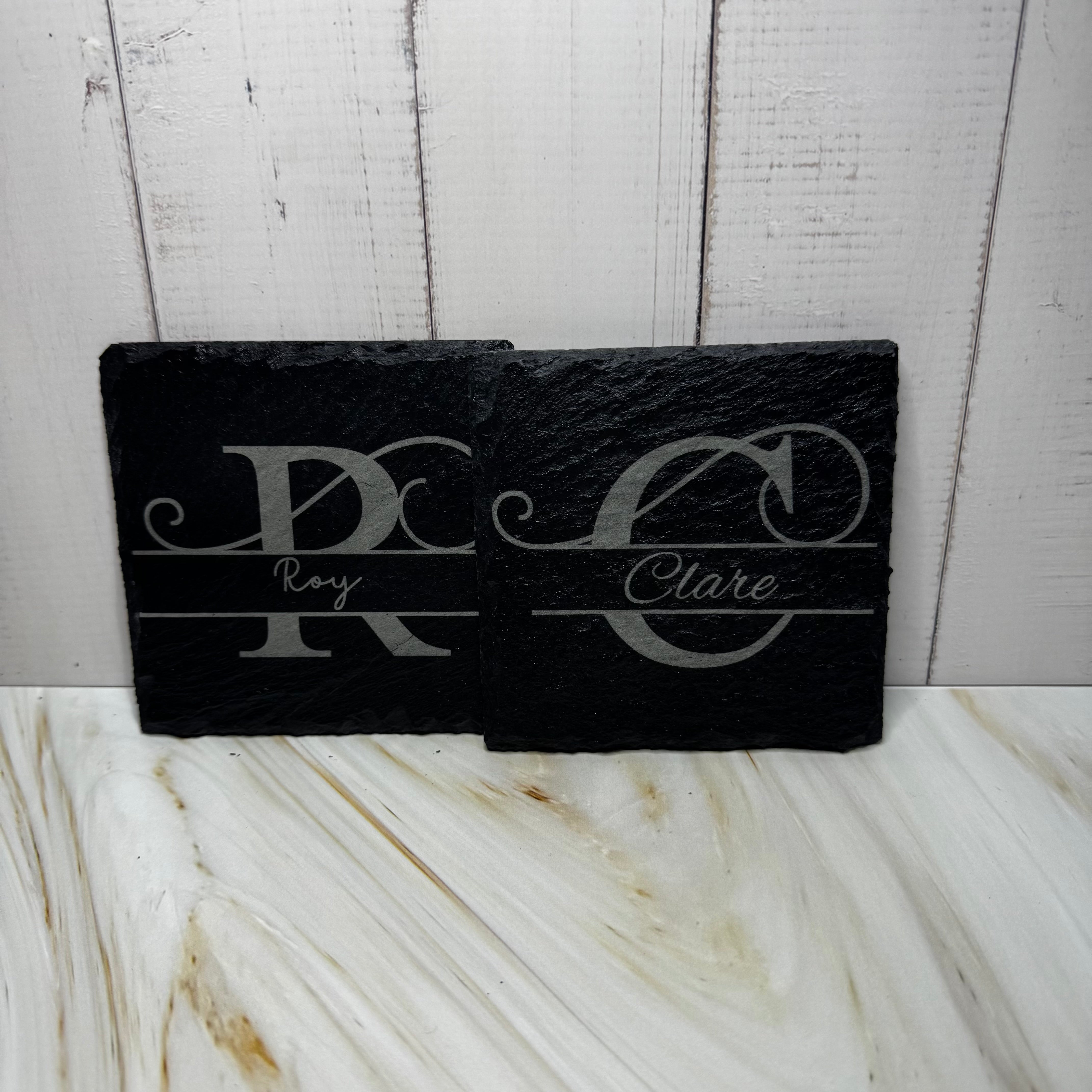 Black slate with engraved initials and names on a marble surface with wooden background