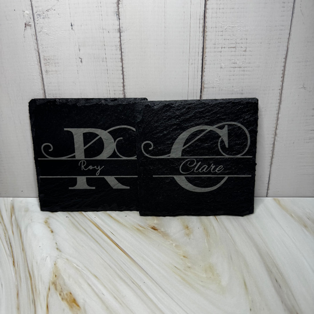 Black slate with engraved initials and names on a marble surface with wooden background