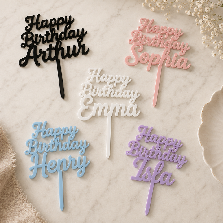 Personalized 'Happy Birthday' cake toppers in various colors on a marble surface.