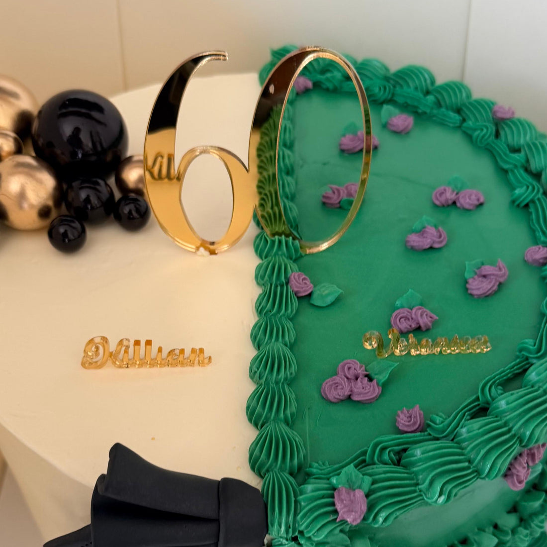 Decorative cake with green icing, black bow, and gold accents on a white background
