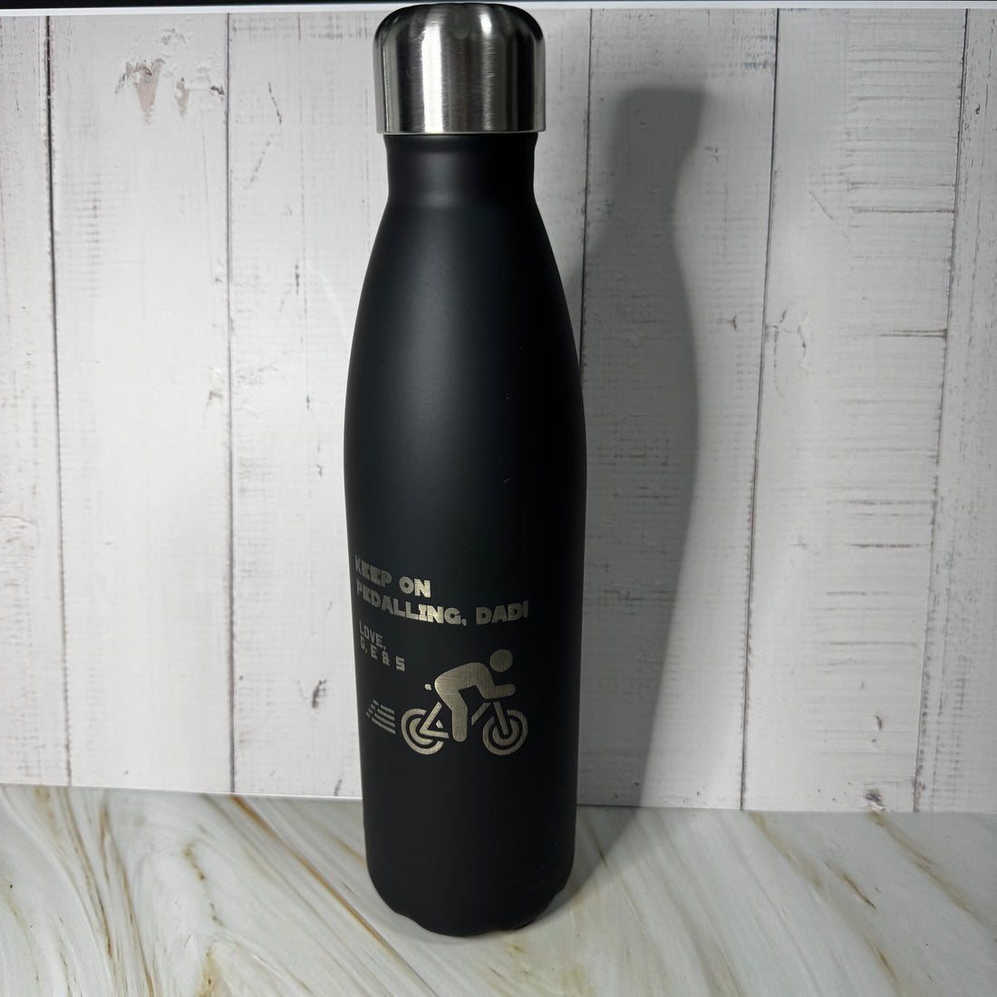 Black water bottle with a silver cap on a wooden surface