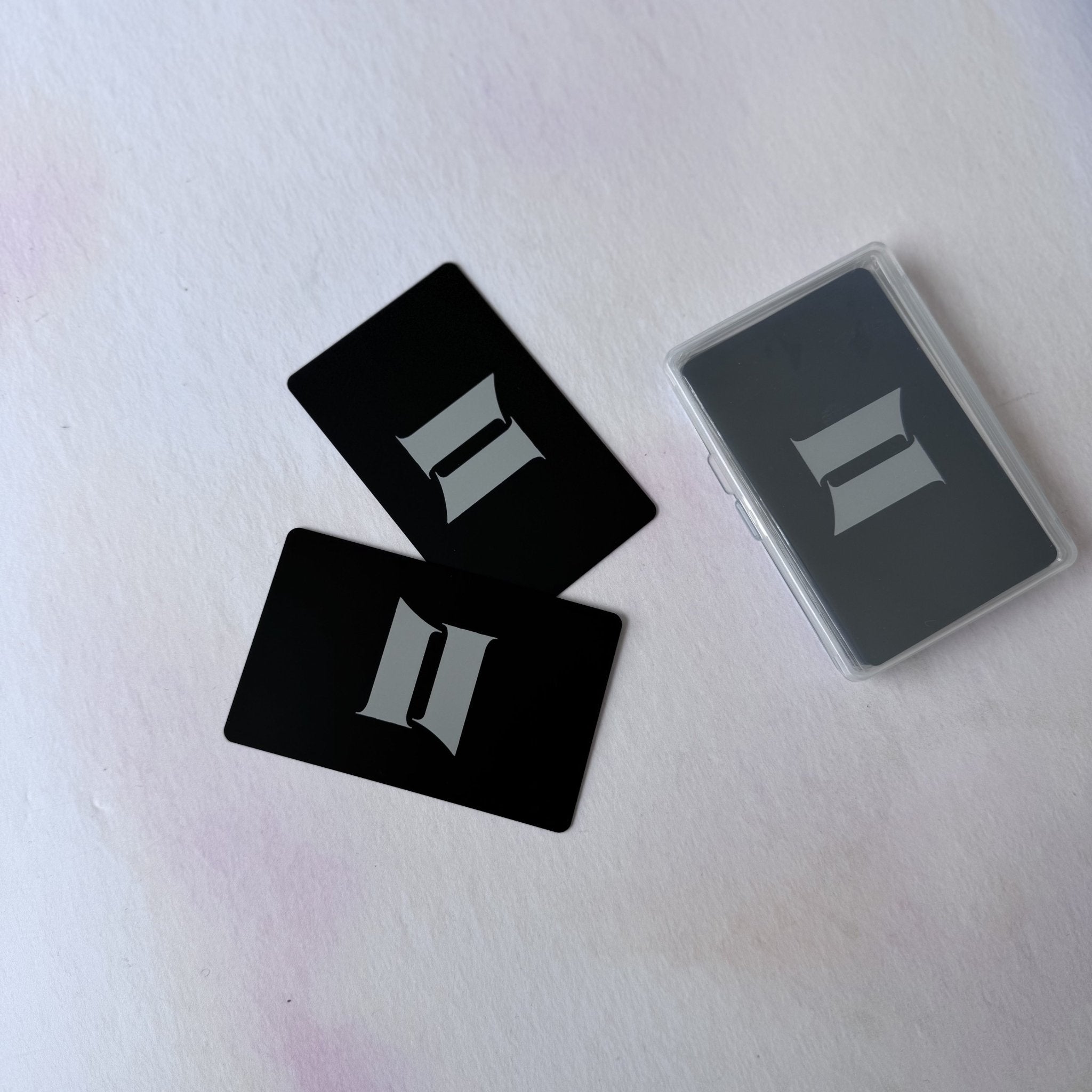 Black metal cards with engraved initials beside clear storage case – personalised metal business card – Etch 'N' Shine