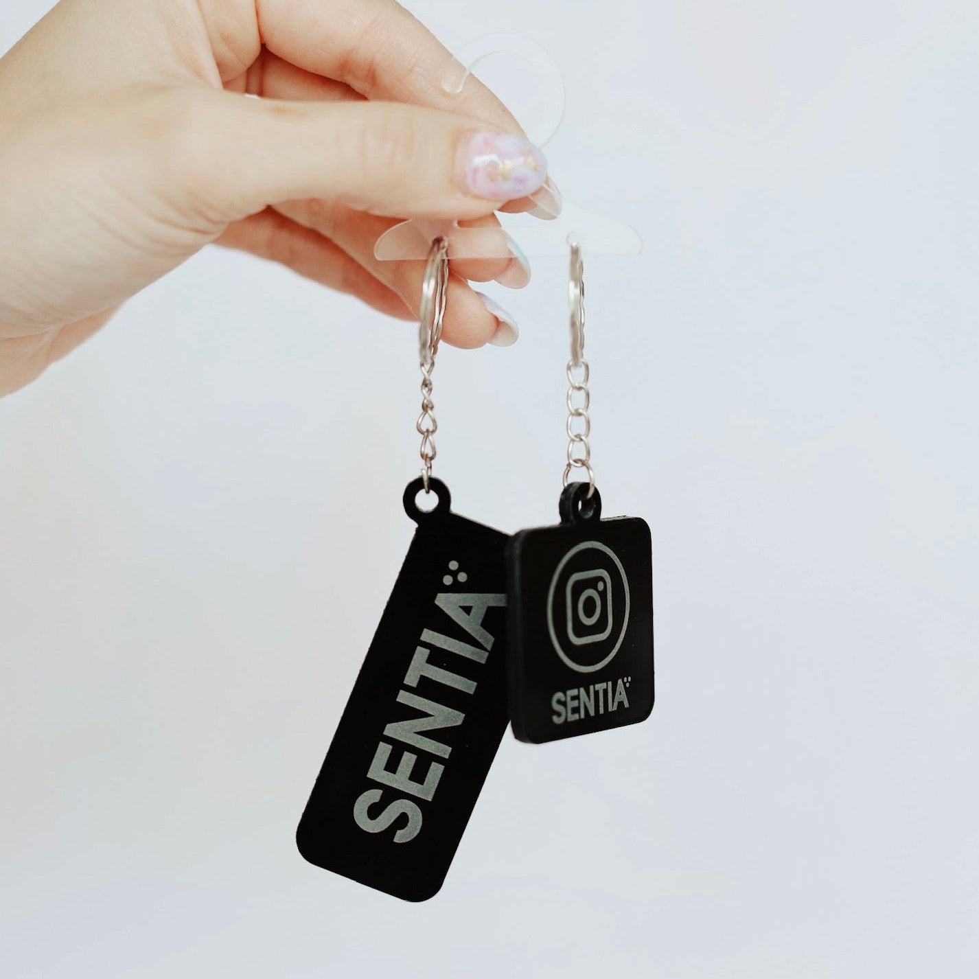 Hand holding two black acrylic keyrings with custom text – personalised NFC acrylic keyring – Etch 'N' Shine