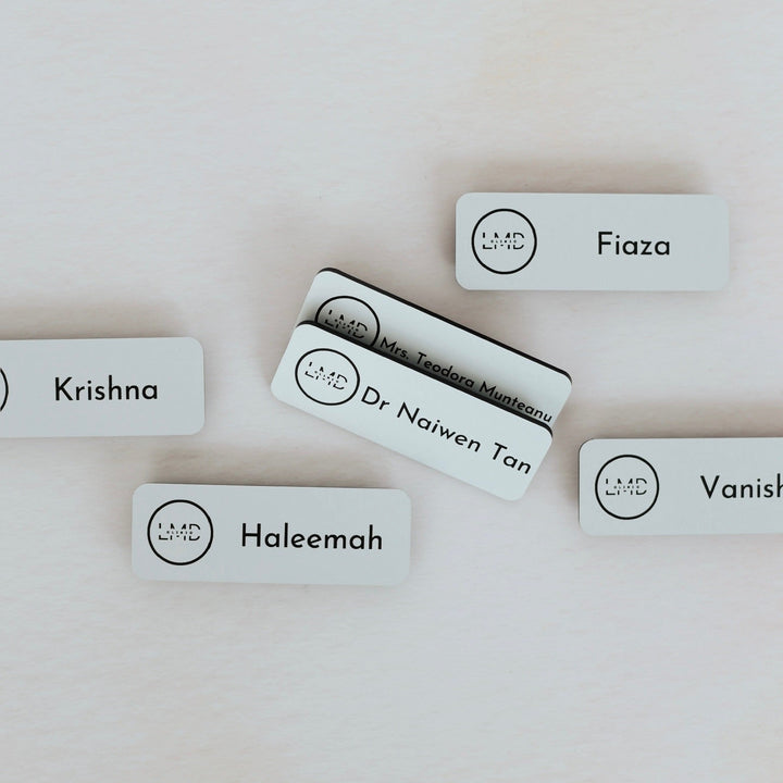 Several white acrylic name badges with custom names and logo – engraved name badges – Etch 'N' Shine