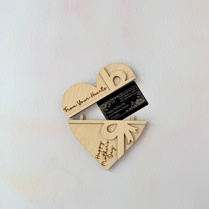Wooden heart-shaped card holder with engraved text on a light gray background