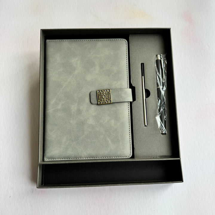 Gray planner and pen set in a black box on a light gray background