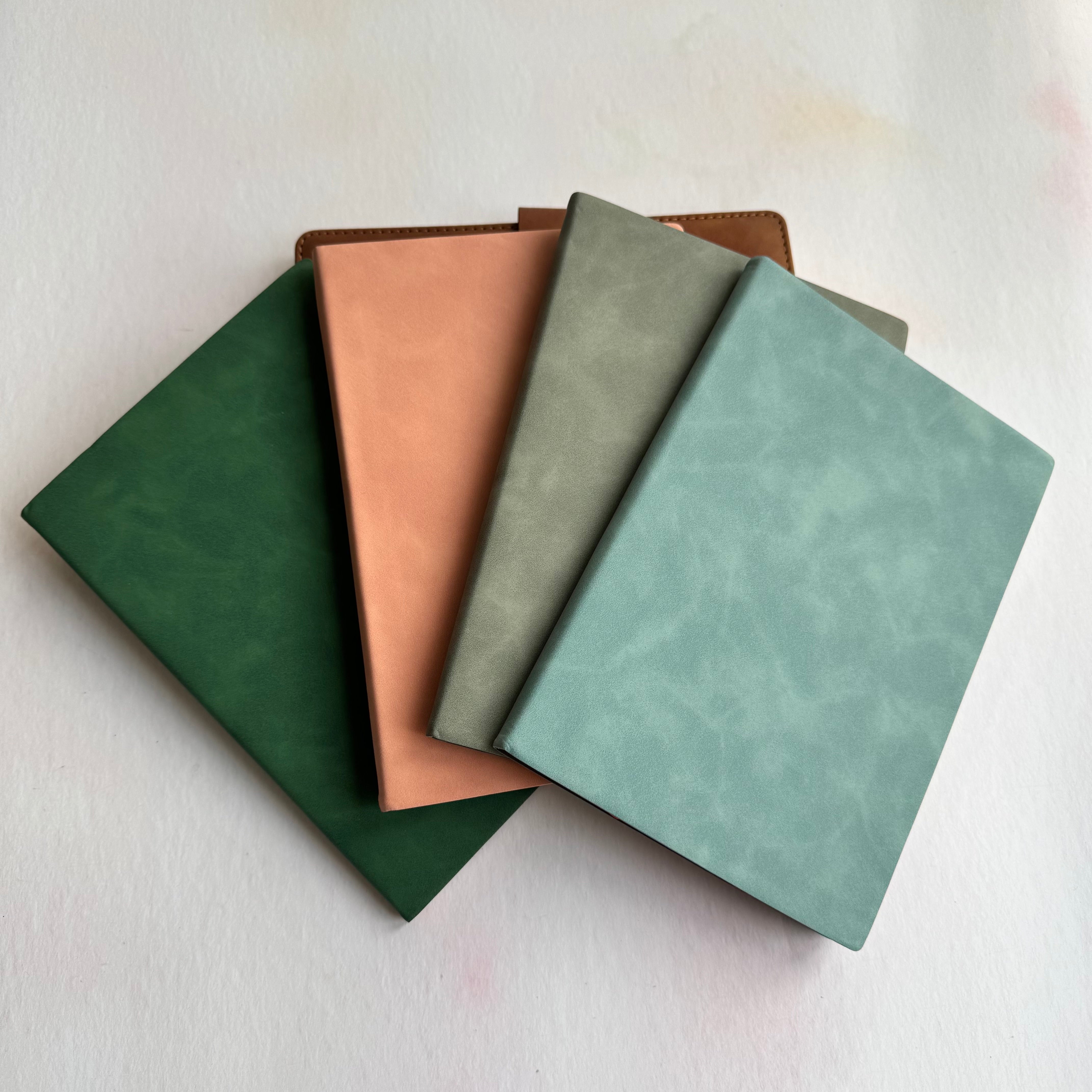 Four leather-bound books in different colors on a light background