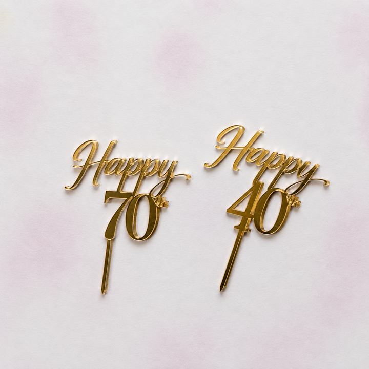 Two gold cake toppers with 'Happy 70th' and 'Happy 40th' text on a light gradient background.