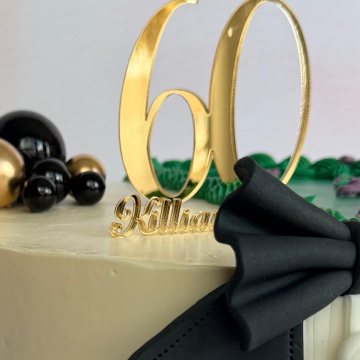 Decorative cake with gold number '60' and black bow on a light background