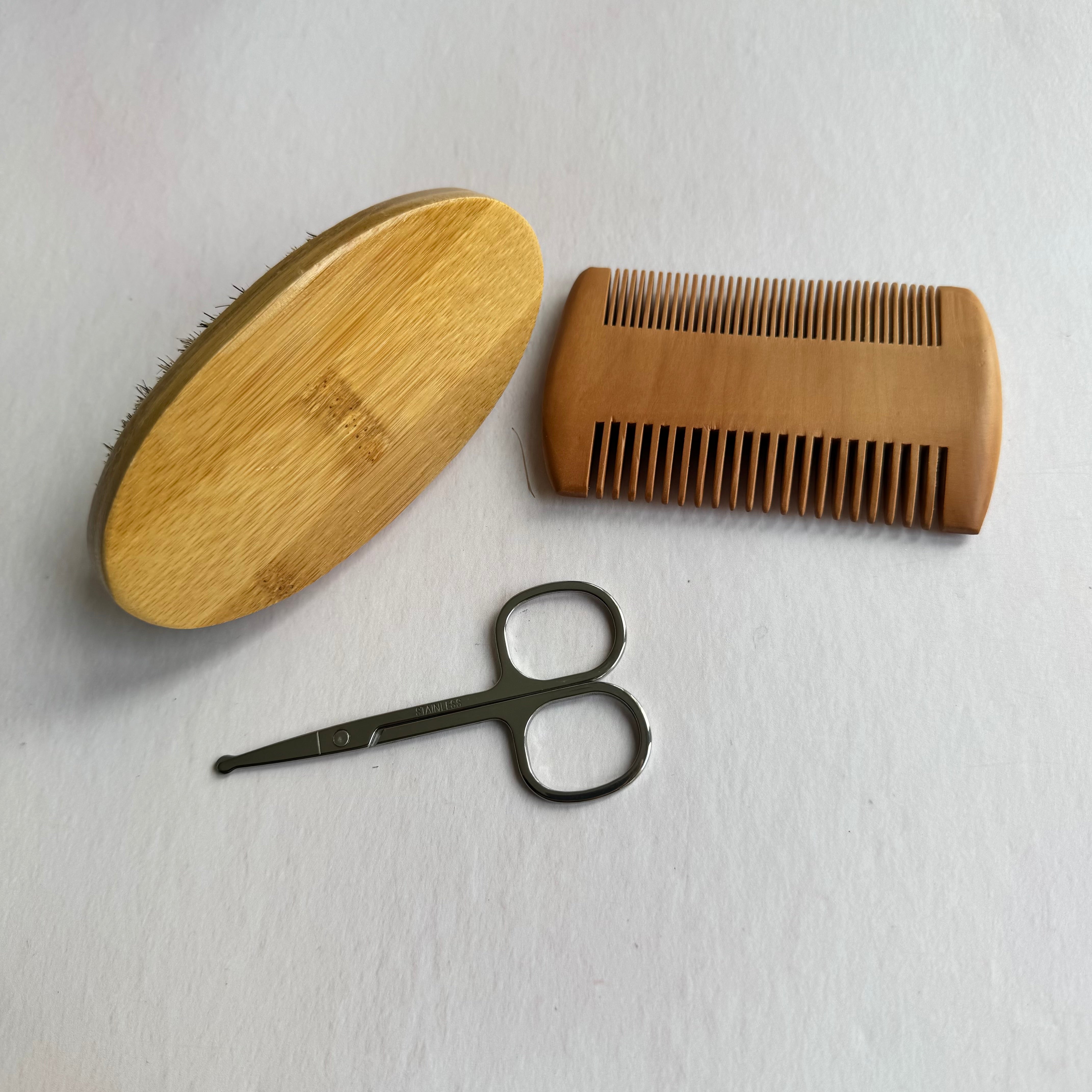 Wooden brush, comb, and scissors on a white background