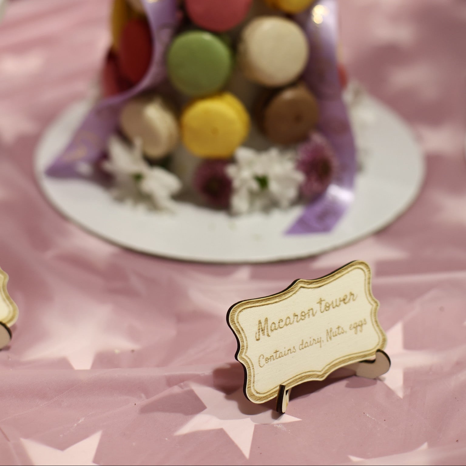 Engraved wooden food sign on stand with custom text, placed on a table beside a macaron display – Etch 'N' Shine
